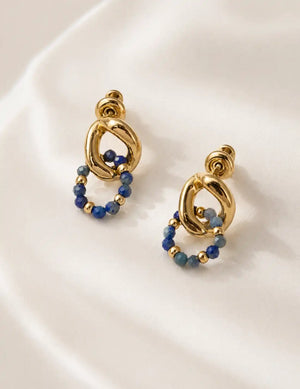 Empires Lapis Lazuli Drop Earrings in 18K gold with blue lapis lazuli stones, photographed on soft white fabric for a luxury jewellery look.