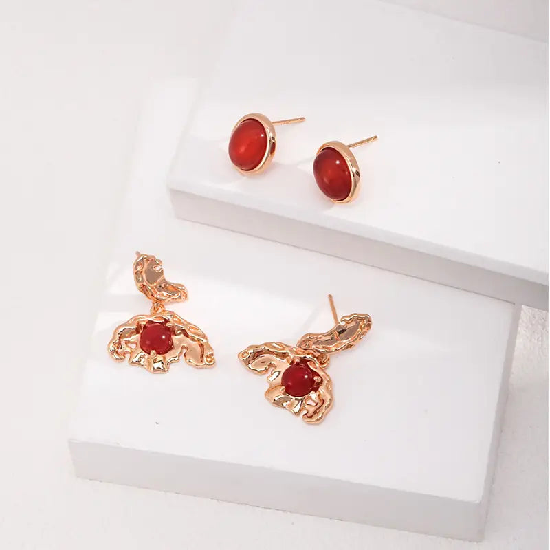 Flat lay of Aimee red agate earrings with gold butterfly design by Anaïs & Aimee UK.