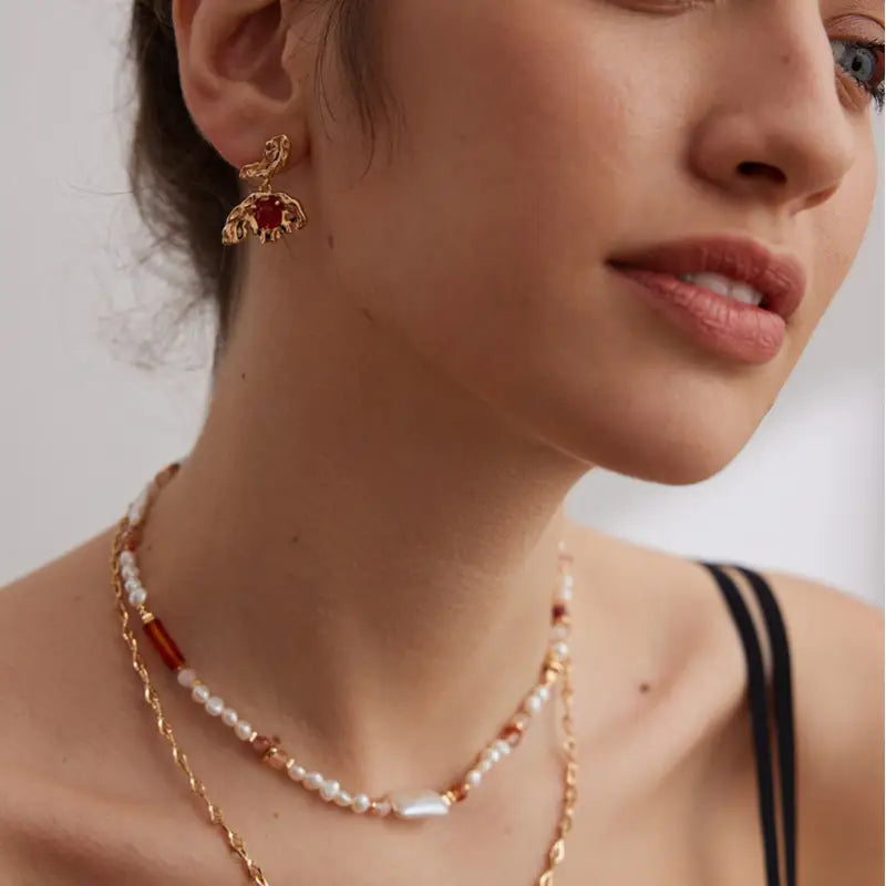 Side profile of model wearing Aimee red agate stud earrings with organic gold design.