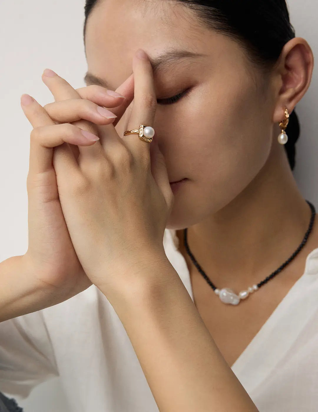 Woman wearing pearl jewelry with a neutral background