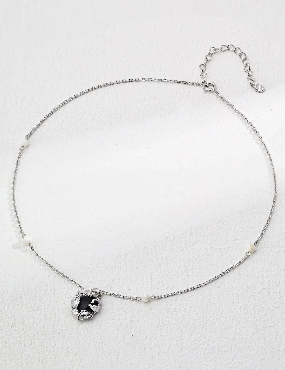 Close-up of silver wire shell necklace with black agate-inspired gemstone and intricate detailing.
