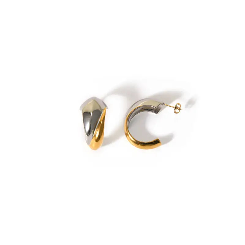 A pair of organic mixed metal hoop earrings with a gold plated stainless steel design, featuring a sleek C-shaped structure.