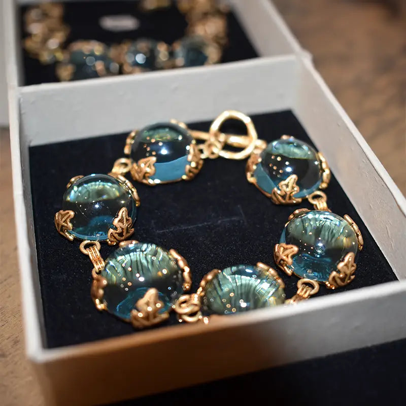 Close-up of Patchouli Bristol Blue Glass Bracelet with blue stones in gold frames