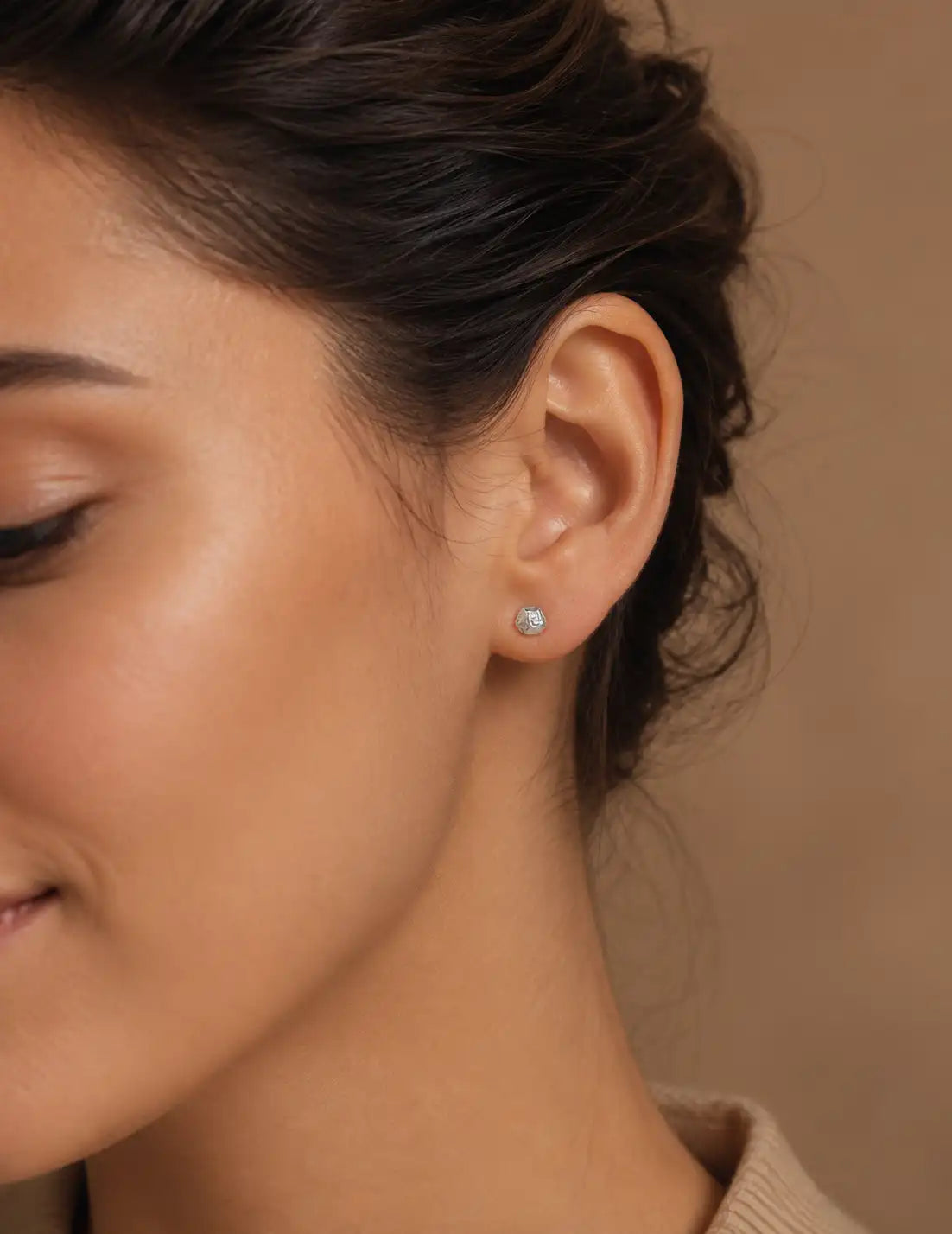 Detailed close-up of textured silver stud earrings with an organic sculptural finish, worn on the ear for a refined minimalist jewellery style.