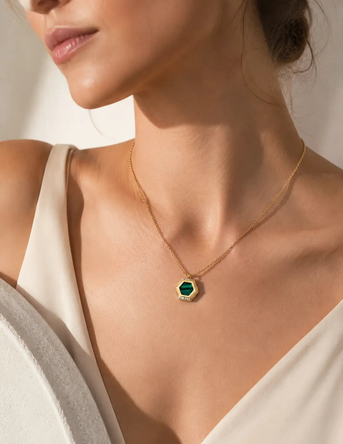 Close-up of the Malachite Pendant Necklace with a geometric hexagon pendant, natural green malachite stone and vintage gold chain worn on the neckline.