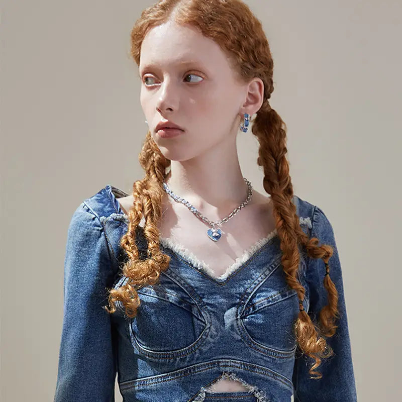 Side profile of model wearing Denim Heart silver necklace and denim hoop earrings.