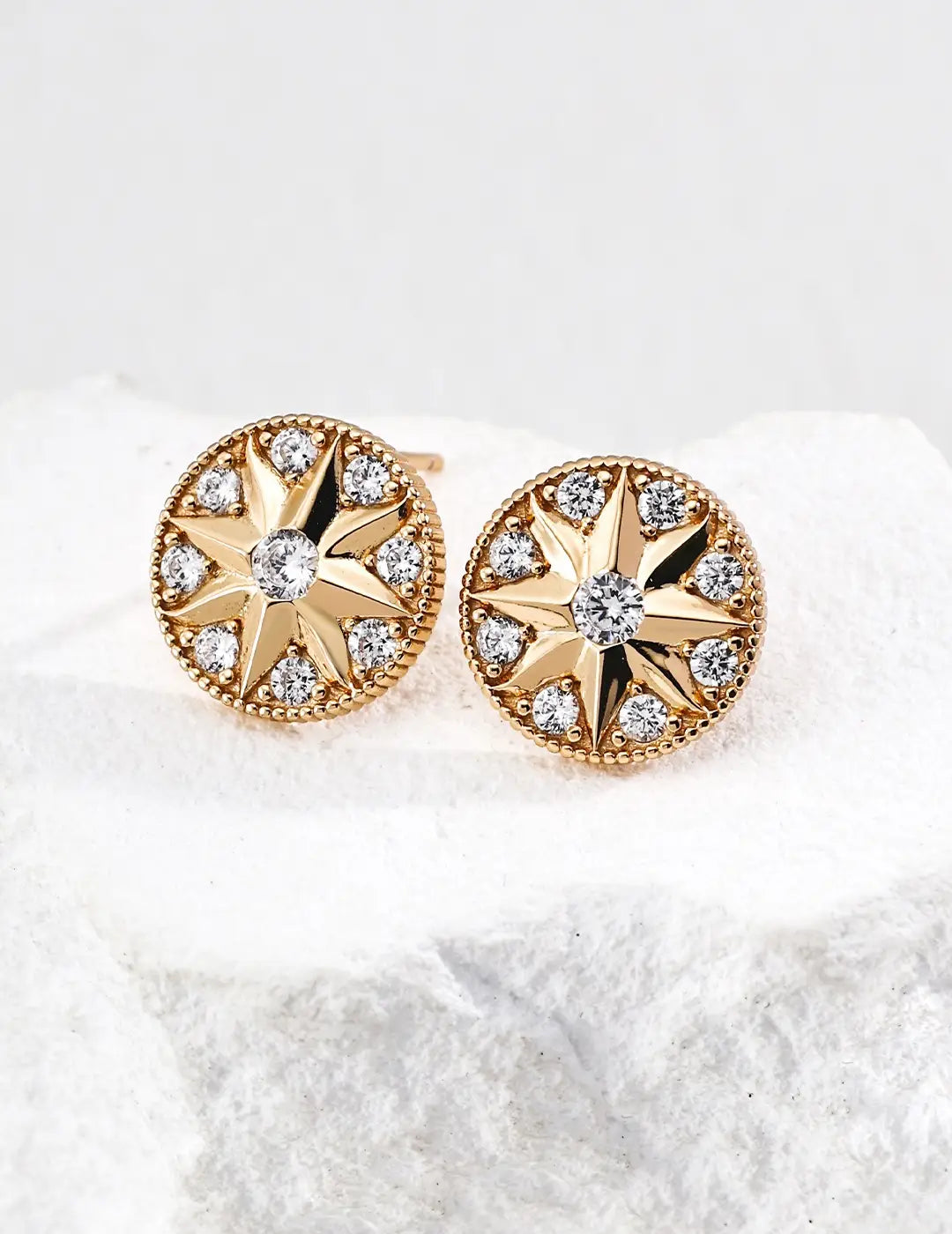 Gold earrings with diamond accents on a white background