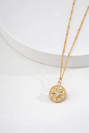 Gold necklace with a circular pendant on a white background