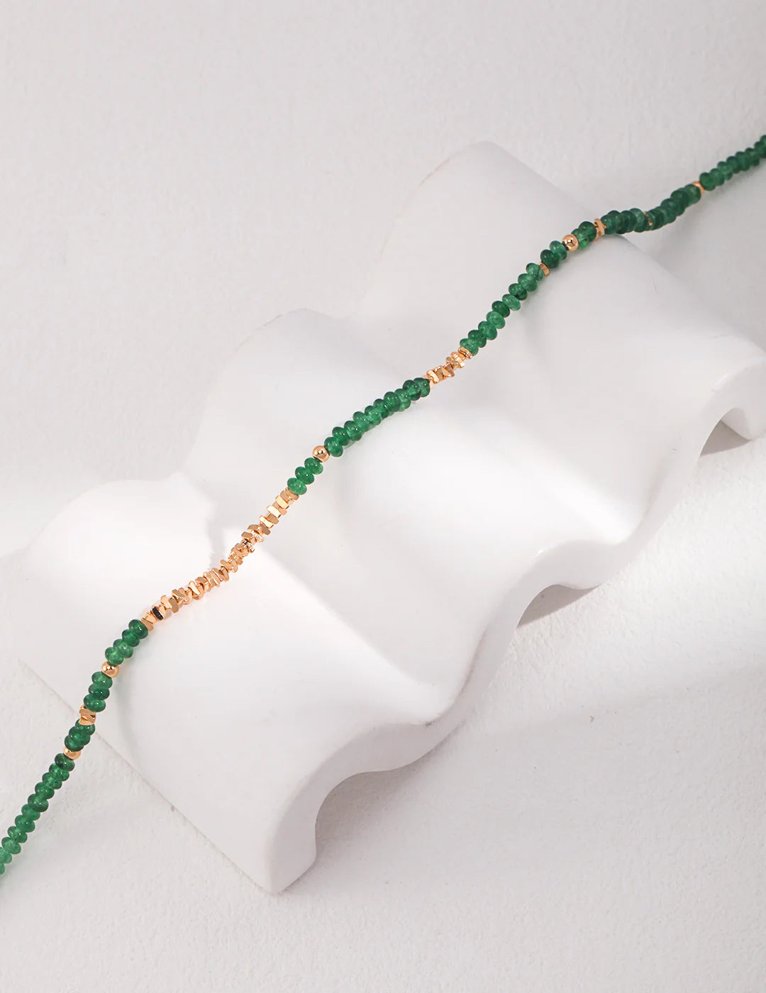 Emerald Green Necklace Choker with gold stones by Anaïs & Aimee on white curved stand.