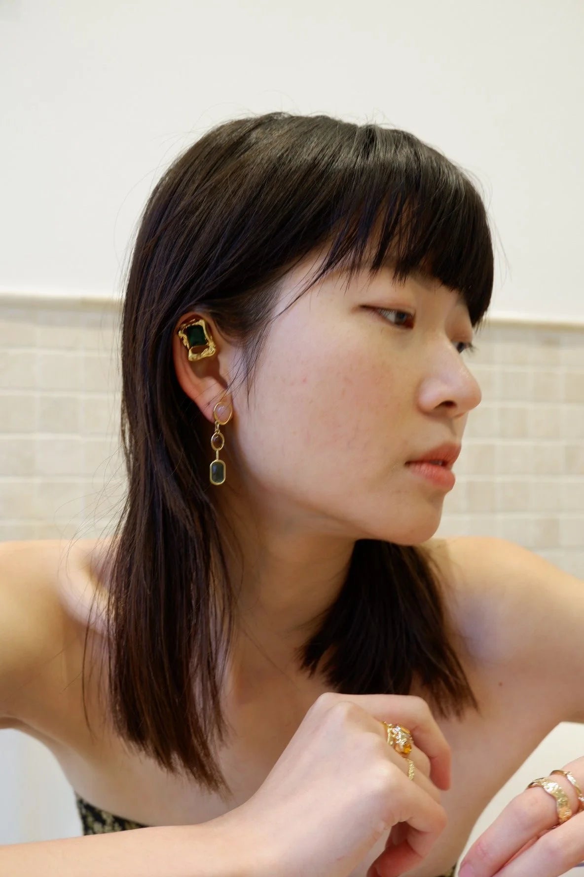Model wearing Emerald Crystal Studs with gold dangle earrings for a modern, stylish look.