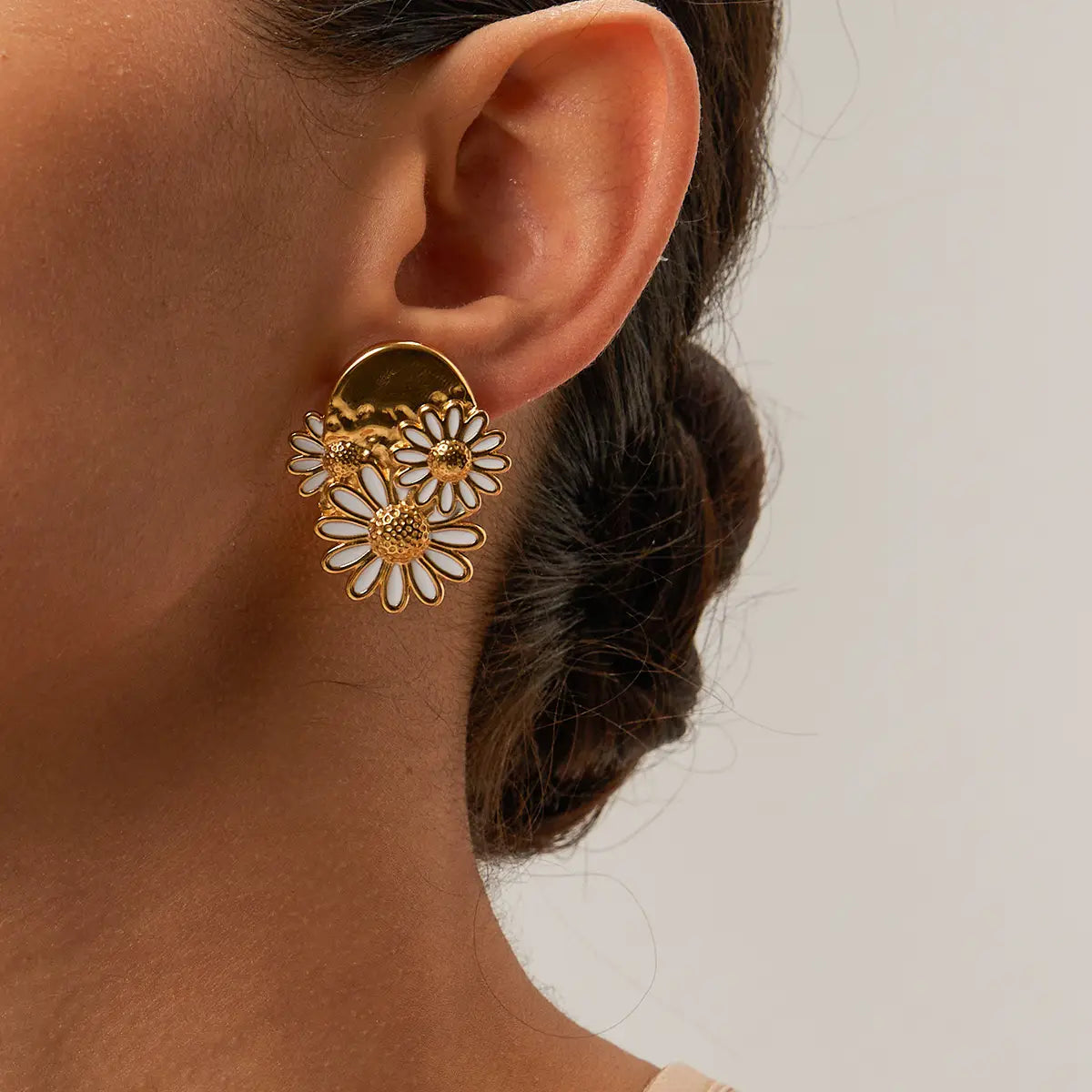 Close-up of woman wearing handmade gold daisy floral statement earrings by Anais&Aimee