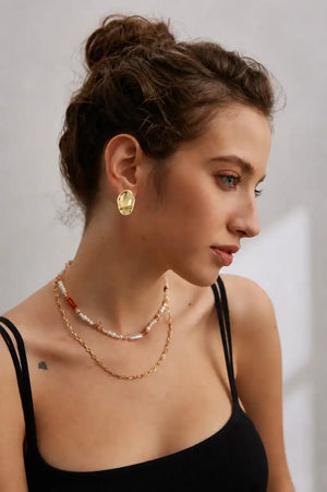 Model wearing Essence sculptural gold statement earrings with a polished organic finish.