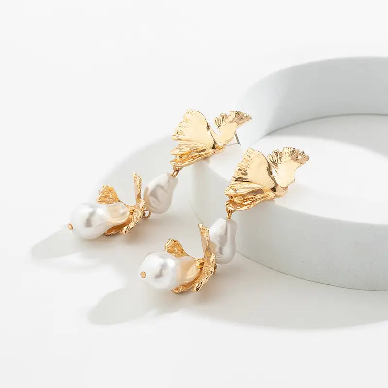 Gold leaf earrings with detailed veins, each featuring unique baroque pearls for elegance