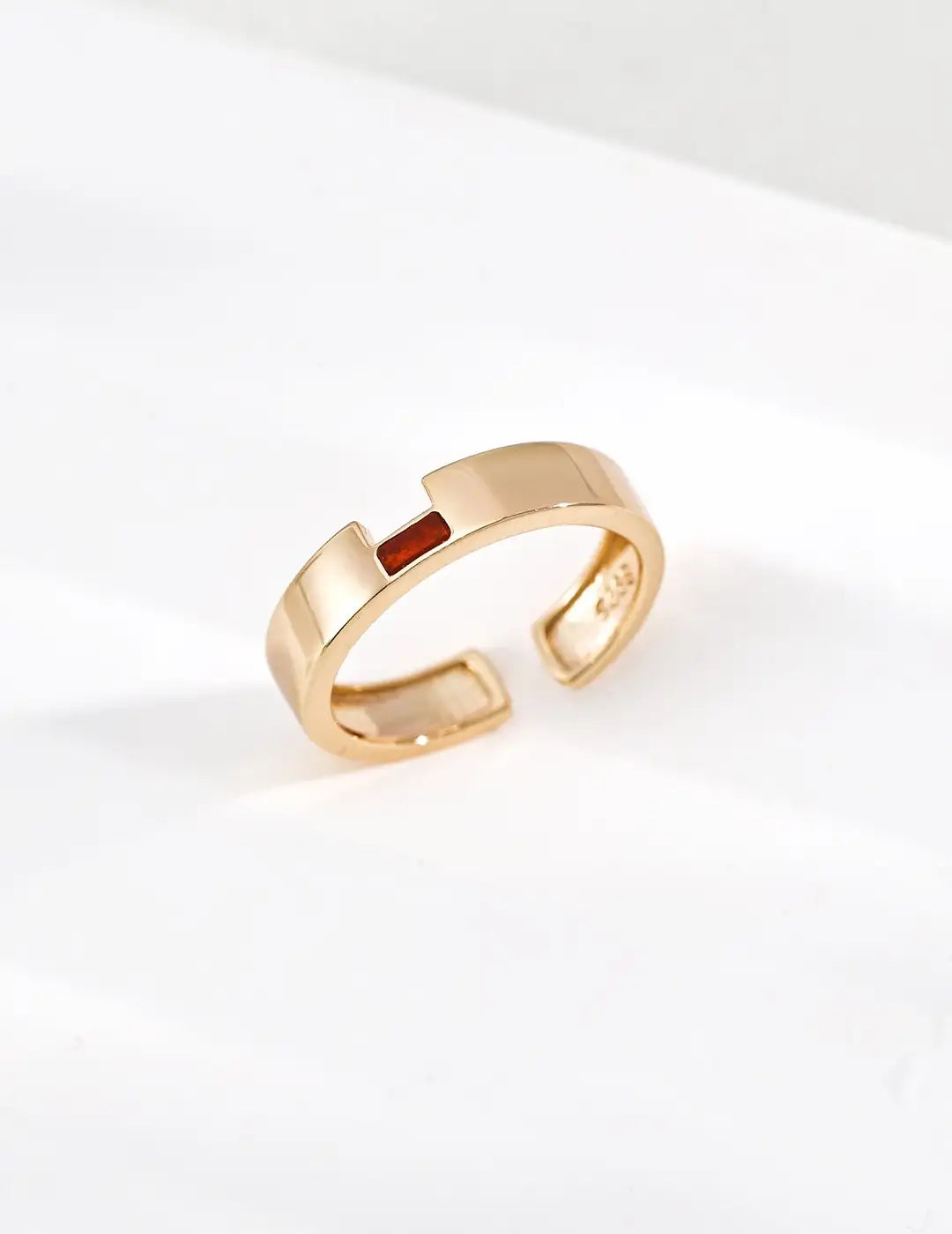 Gold ring with a red stone on a white background