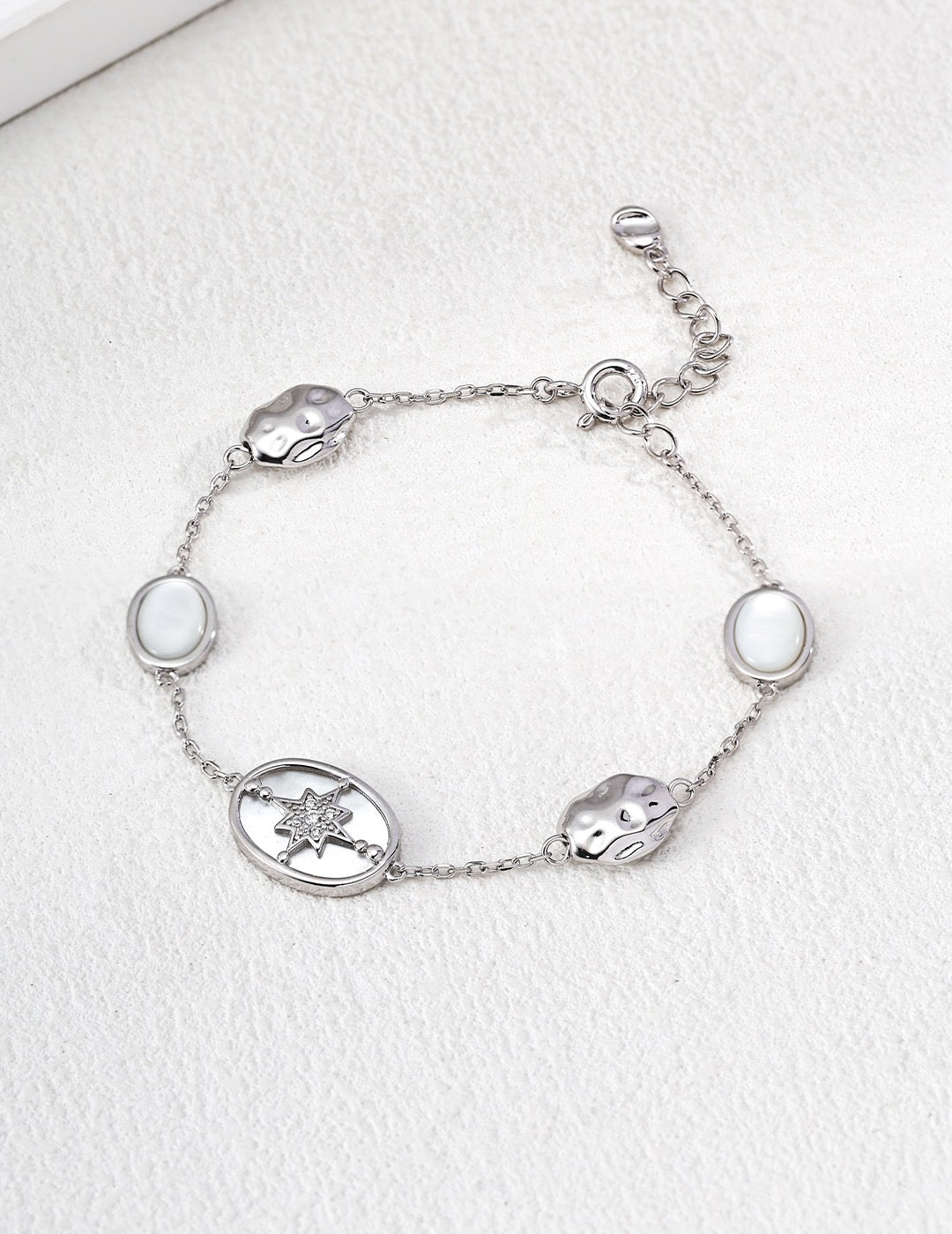 Silver bracelet with various charms on a white background