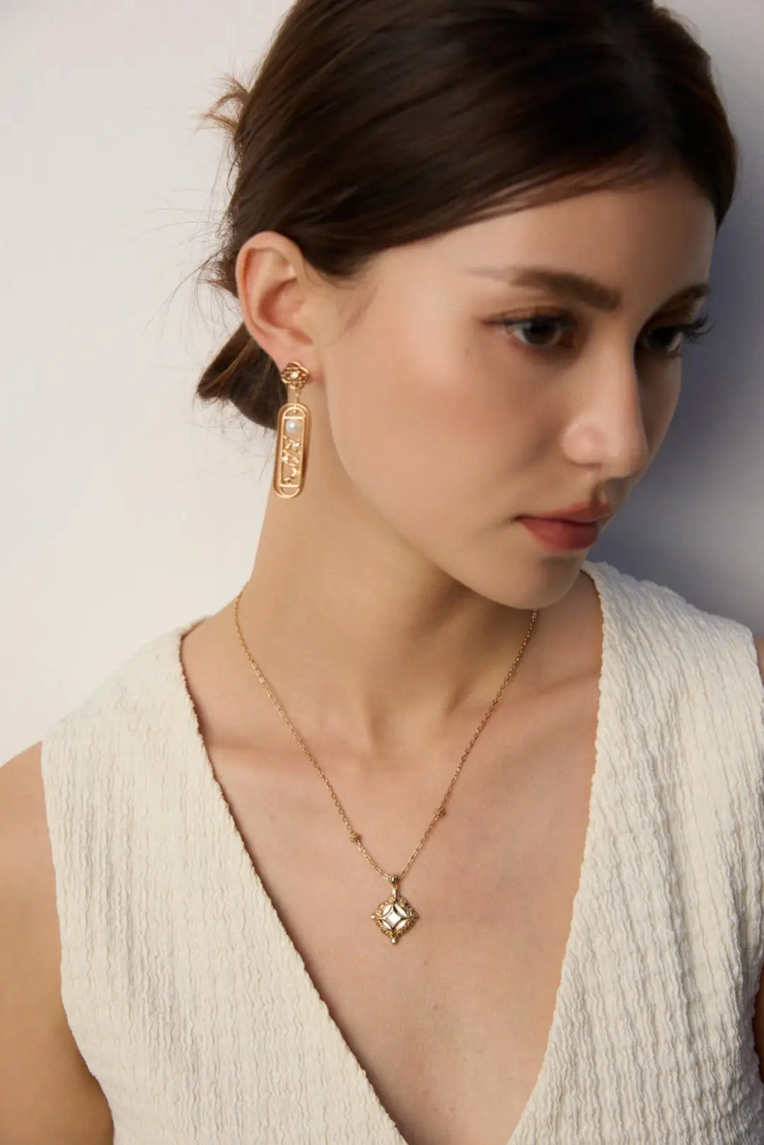 Model wearing Haslemere gold square pendant necklace with mother of pearl centre and zircon detail.