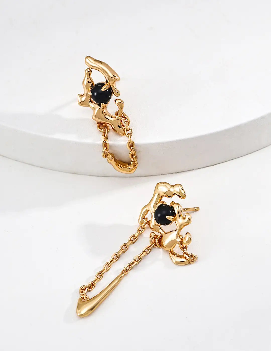 Gold cat-shaped earrings with black gemstones on a white background
