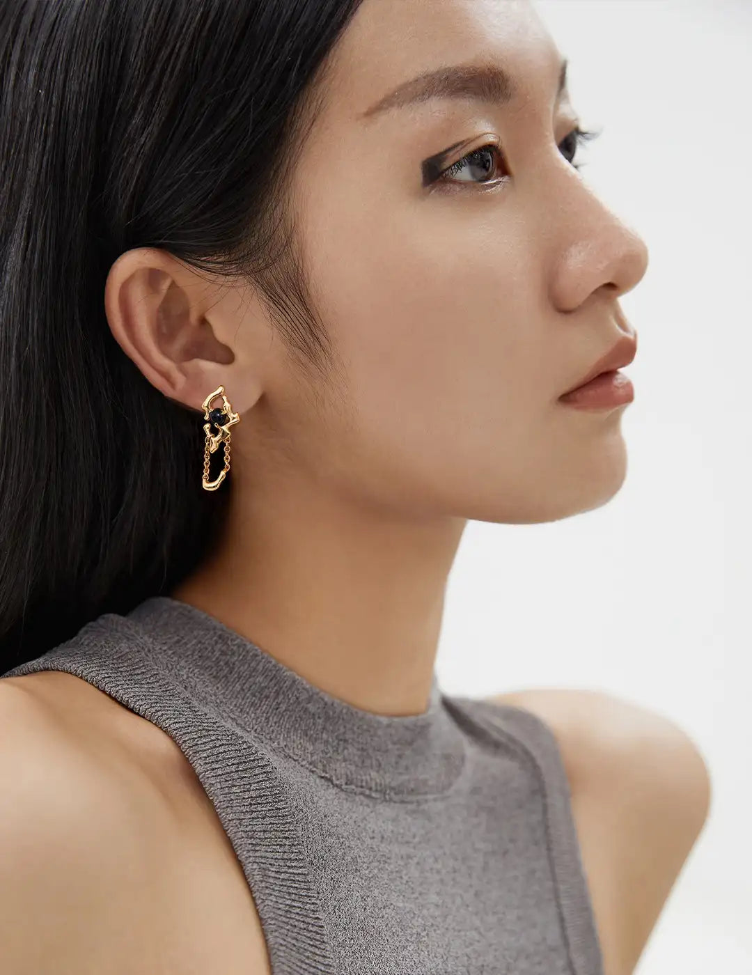 Close-up of a woman wearing a gold earring with a neutral background