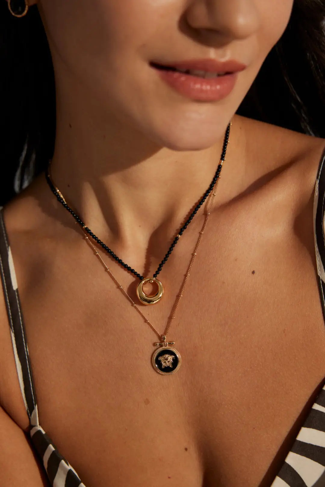 Lunar Circle black agate necklace on white tiers, highlighting beads and gold accents
