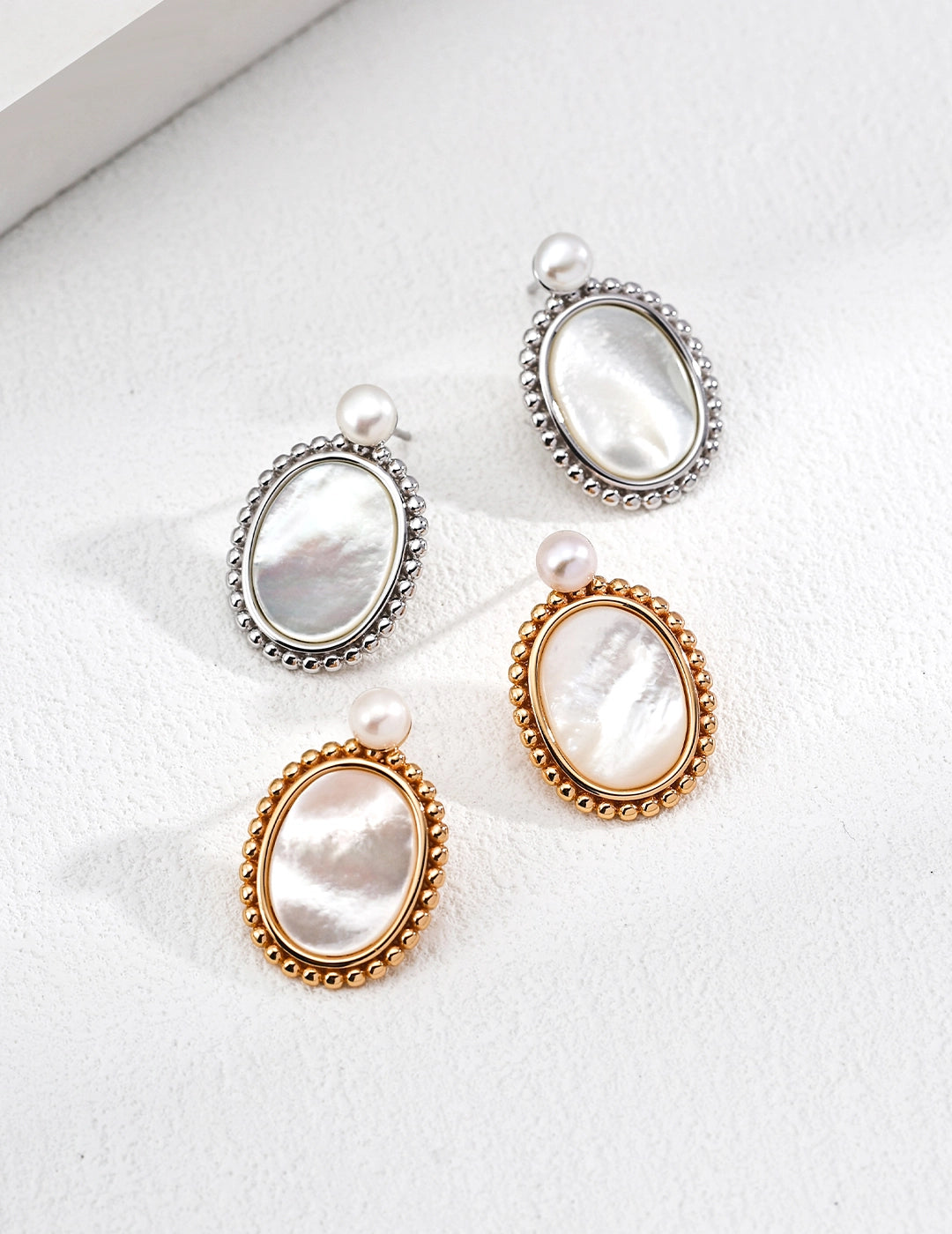 Set of three earrings with pearl-like stones on a white background