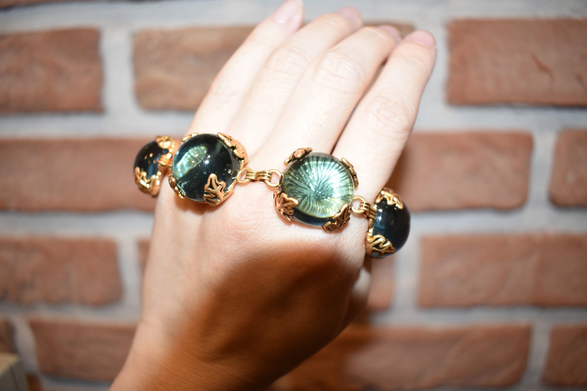 Close-up of Patchouli Bristol Blue Glass Bracelet with large blue stones in gold.