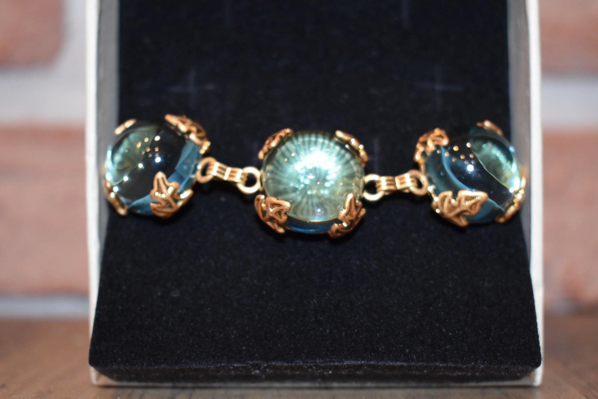 Close-up of Patchouli Bristol Blue Glass Bracelet with gold leaf settings in jewelry box