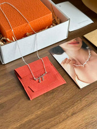 Necklace on a red card with an orange box and magazine in the background