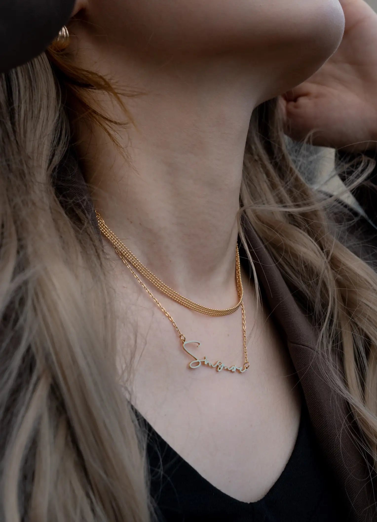 Close-up of a person wearing a delicate gold necklace with a small pendant.