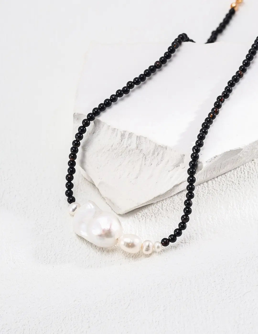 Serenity Black Obsidian Pearl Necklace with black stones and white pearls on white platform.