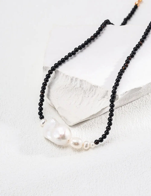 Serenity Black Obsidian Pearl Necklace with black stones and white pearls on white platform.