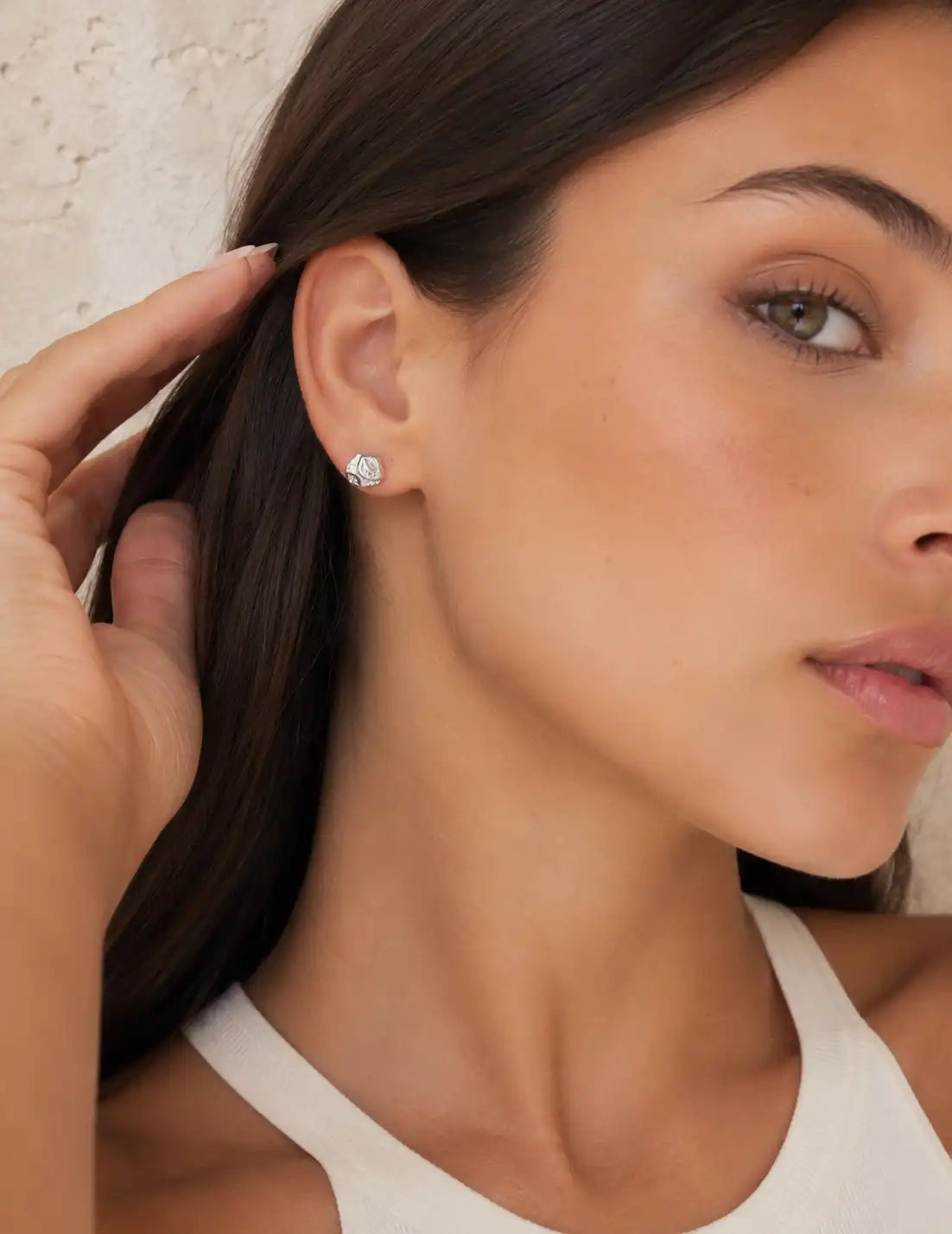 Pair of textured silver stud earrings photographed on a clean white studio display, highlighting the organic surface detail and polished silver finish.