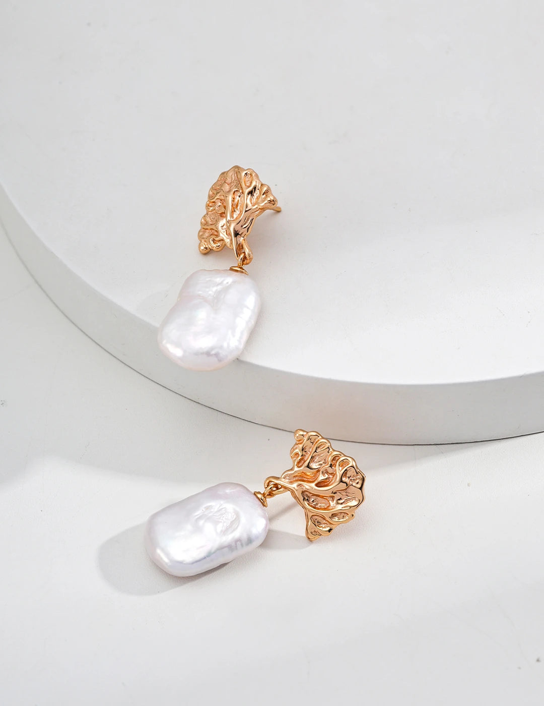 Pair of earrings with gold and pearl design on a white background