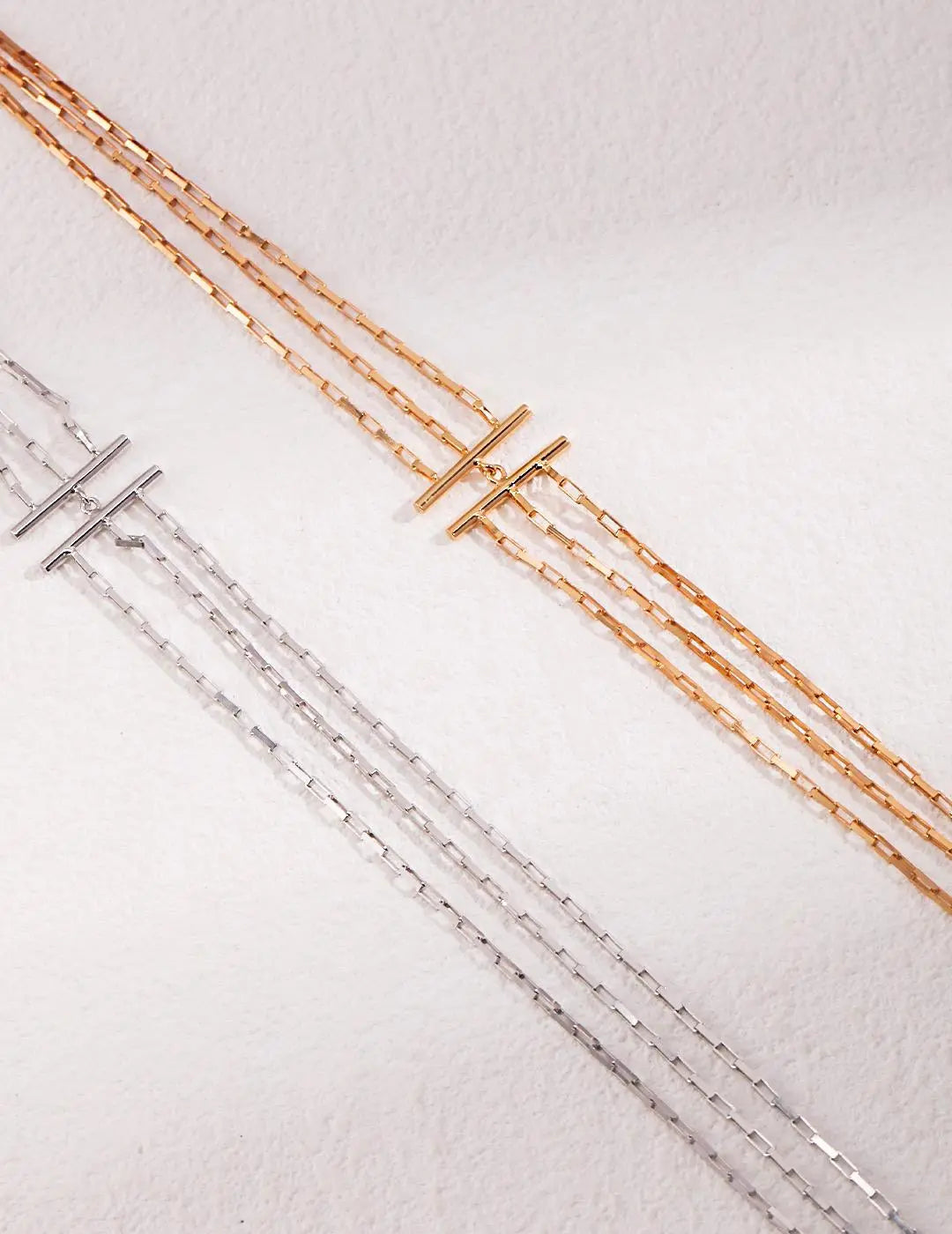 Two gold and silver chain necklaces on a light gray background