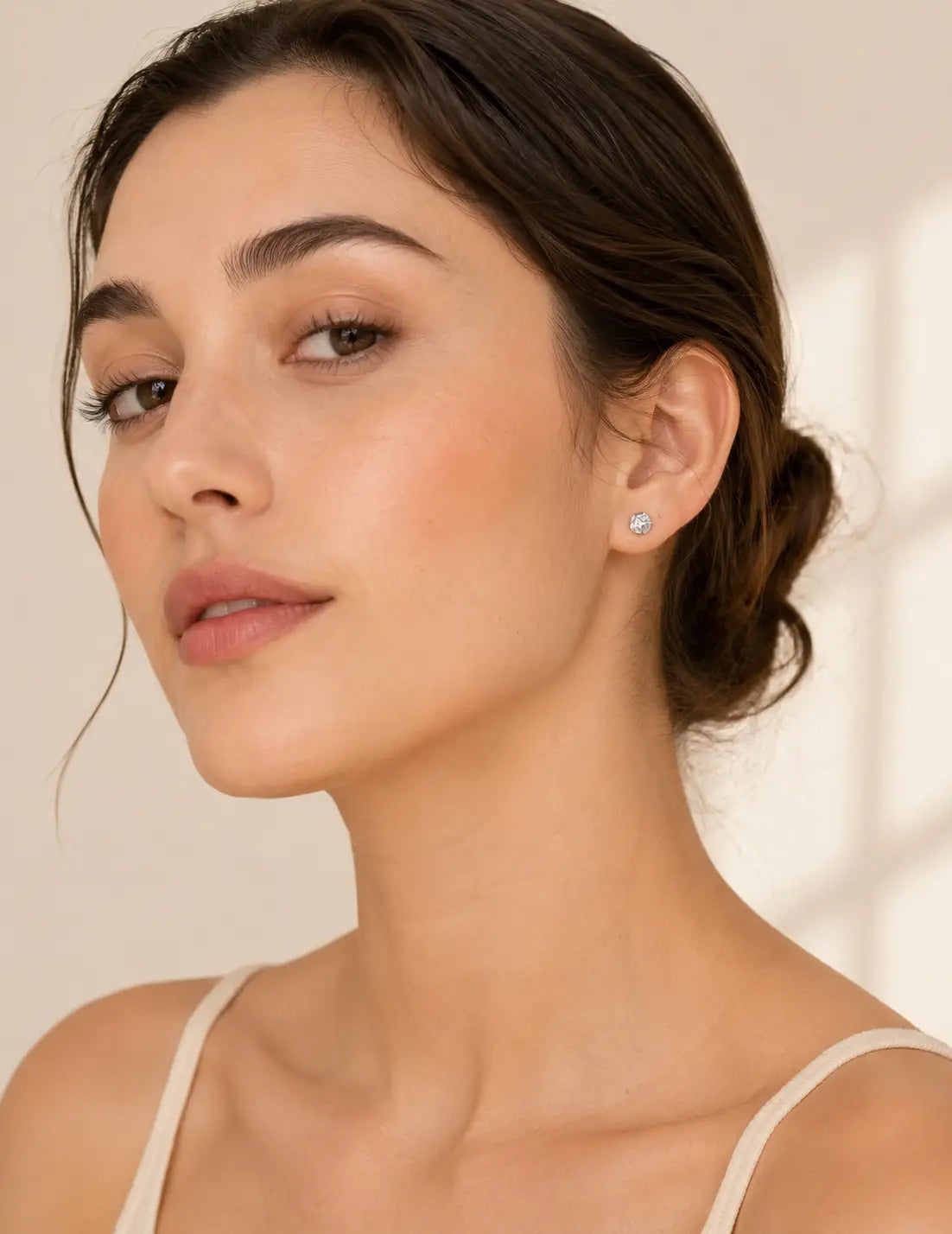 Side profile of a woman wearing reflective silver stud earrings, styled with a black top for a modern minimalist jewellery look.