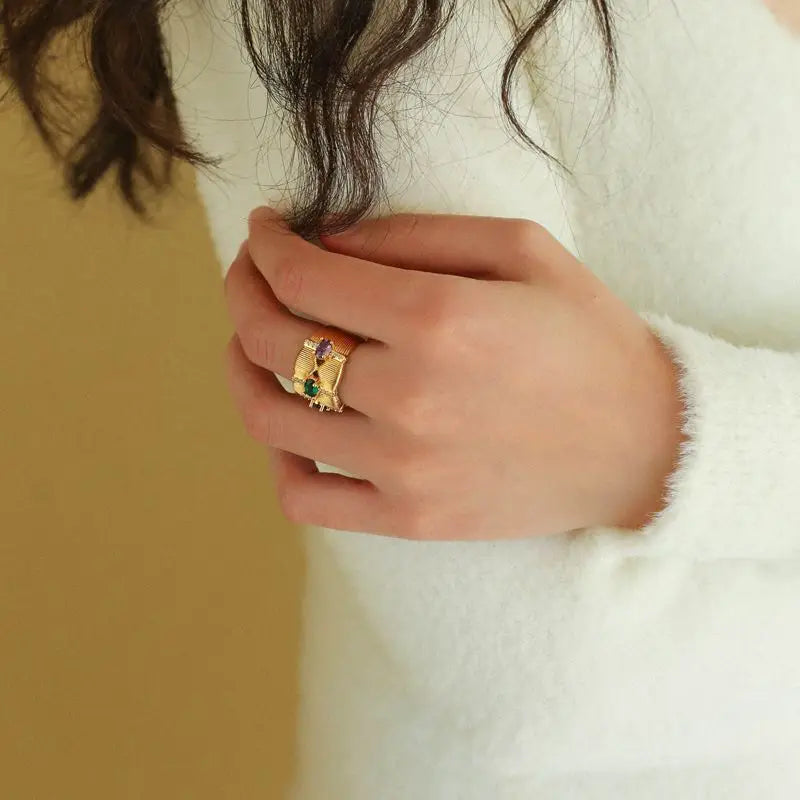Close-up of woman’s hand wearing Radiance Gemstone Ring with green, purple, and red stones.