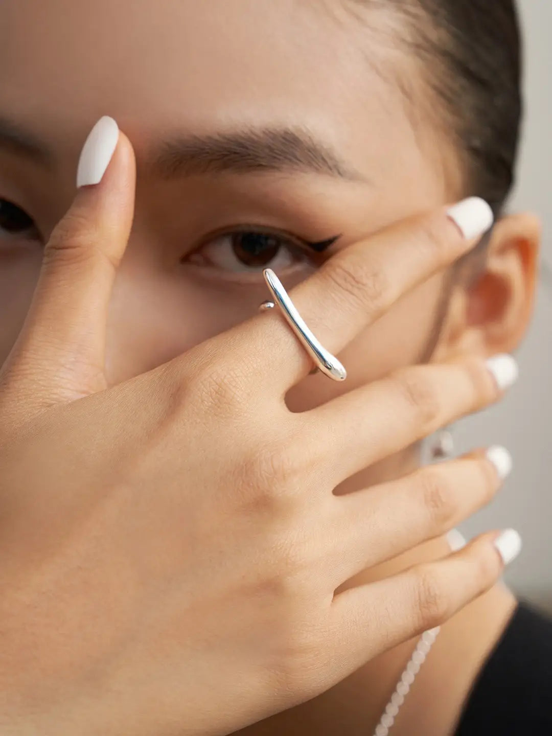 Close-up of a hand with a silver ring on a neutral background , Silver adjustable sterling silver ring on hand – sculptural statement ring UK